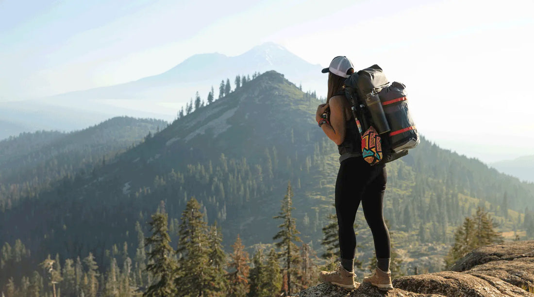 woman standing while hiking and staring at mountains