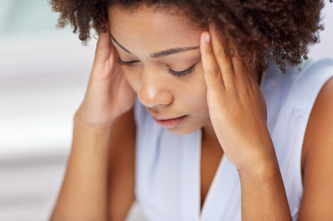 A woman holds her head in her hands, illustrating the impact of stress on POTS symptoms and the importance of stress management POTS.