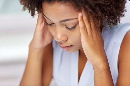 A woman holds her head in her hands, illustrating the impact of stress on POTS symptoms and the importance of stress management POTS.