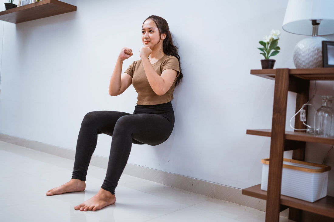 A woman performs a wall sit postural training exercise to help manage her POTS symptoms.
