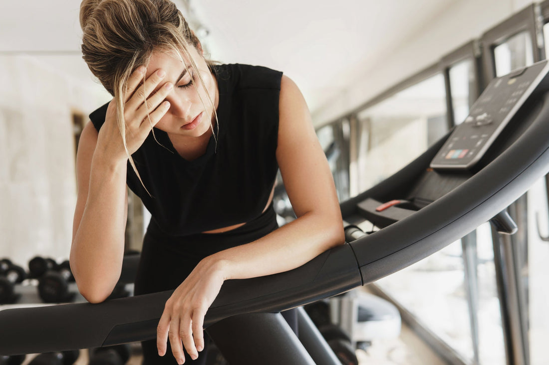 A woman resting on a treadmill, illustrating the challenges of POTS exercise intolerance and the need for tailored low-impact workout strategies.