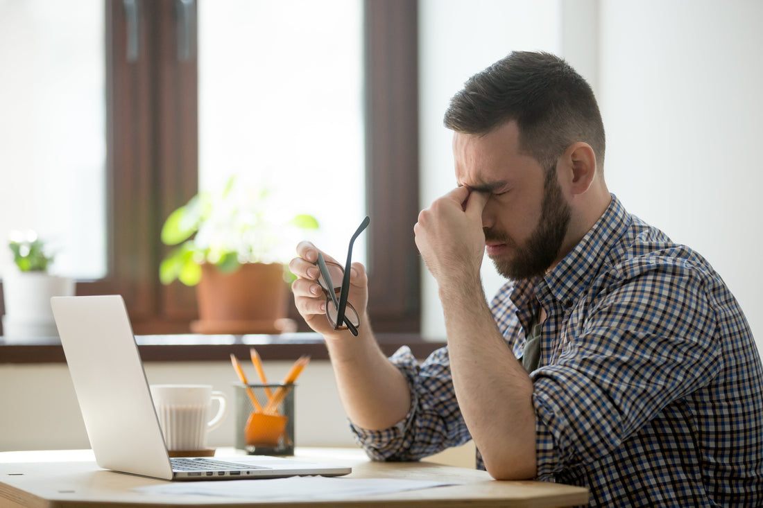 Stressed man experiencing fatigue and brain fog while working at a desk, symbolizing symptoms of chronic fatigue and possible electrolyte imbalance.