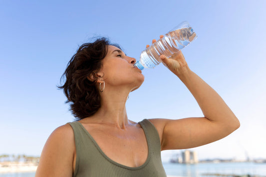 Woman drinking water outdoors to stay hydrated in summer heat