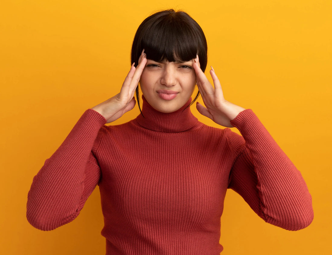 Woman experiencing migraine with aura symptoms holding temples in pain