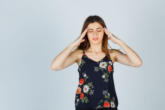 Woman holding her temples experiencing migraine symptoms that illustrate what migraine aura looks like