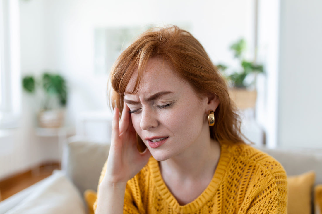 Woman holding her temple in pain experiencing a severe migraine headache and seeking relief indoors