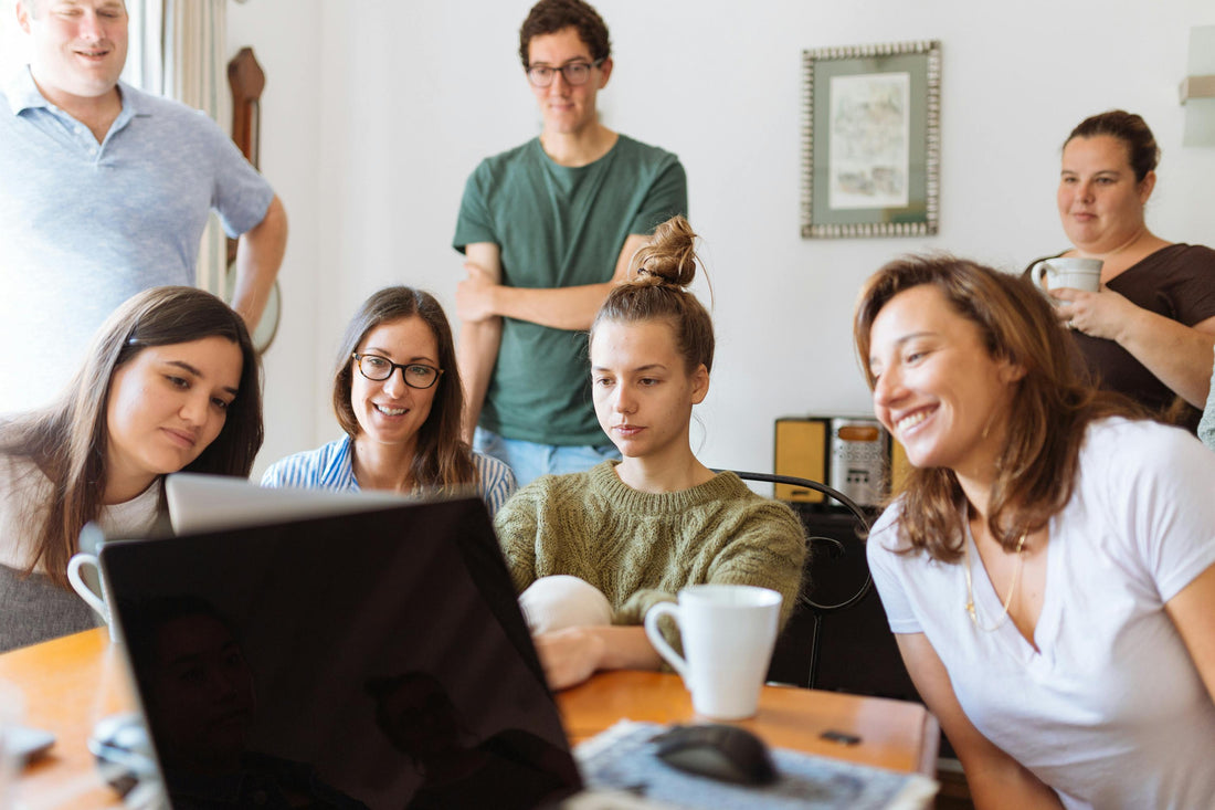 A POTS support group sitting around a table, taking part in an online meeting.