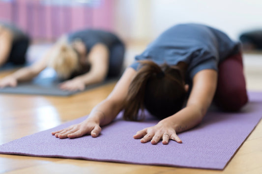 Yoga class participants practice Child’s Pose on yoga mats to promote relaxation and circulation for managing POTS.