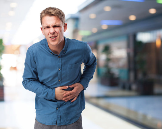 Man holding stomach in pain, showing signs of digestive discomfort, bloating, or gut health issues.