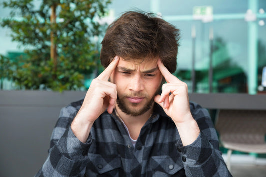 Man experiencing migraine brain fog while holding his temples