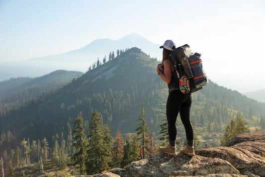 Woman hiking on top of a mountain with a backpack and water bottle.