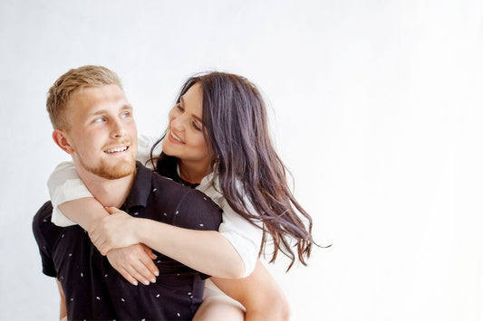 A young woman joyfully embraces a man from behind, portraying a supportive and loving relationship.