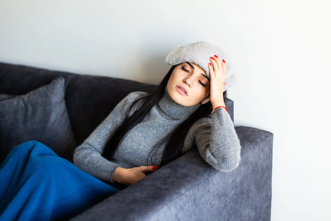 Woman resting on a couch with lingering migraine fatigue, illustrating post-migraine exhaustion after an attack.