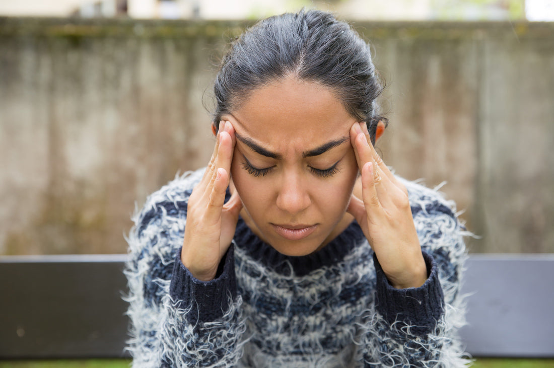 Woman pressing her temples with eyes closed from migraine pain.