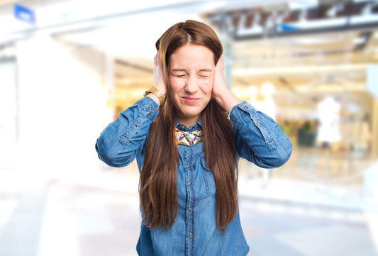 Young woman overwhelmed by bright lights and noise triggering sensory overload migraine symptoms