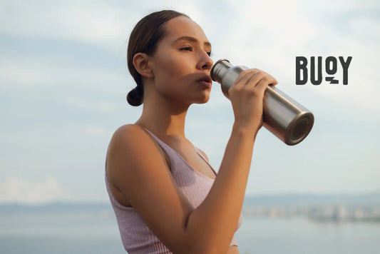 woman drinking water out of a metal bottle
