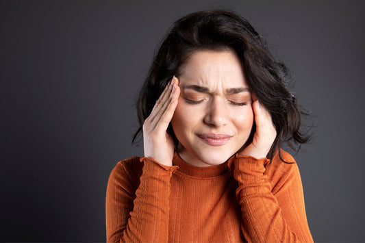 A woman holding her head in discomfort, experiencing symptoms of Postural Orthostatic Tachycardia Syndrome (POTS).