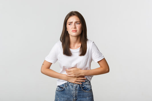 Young woman holding her stomach and looking uncomfortable, showing signs of bloating and digestive discomfort.