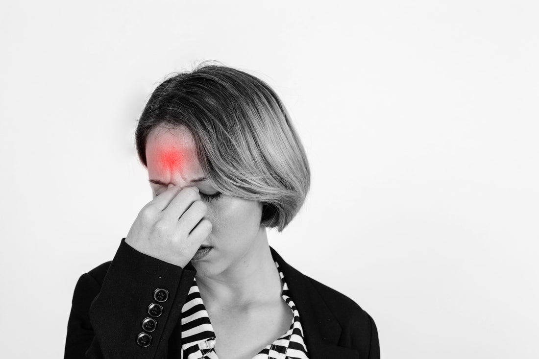 Woman experiencing migraine light sensitivity, holding her forehead with visible pain triggered by bright light.